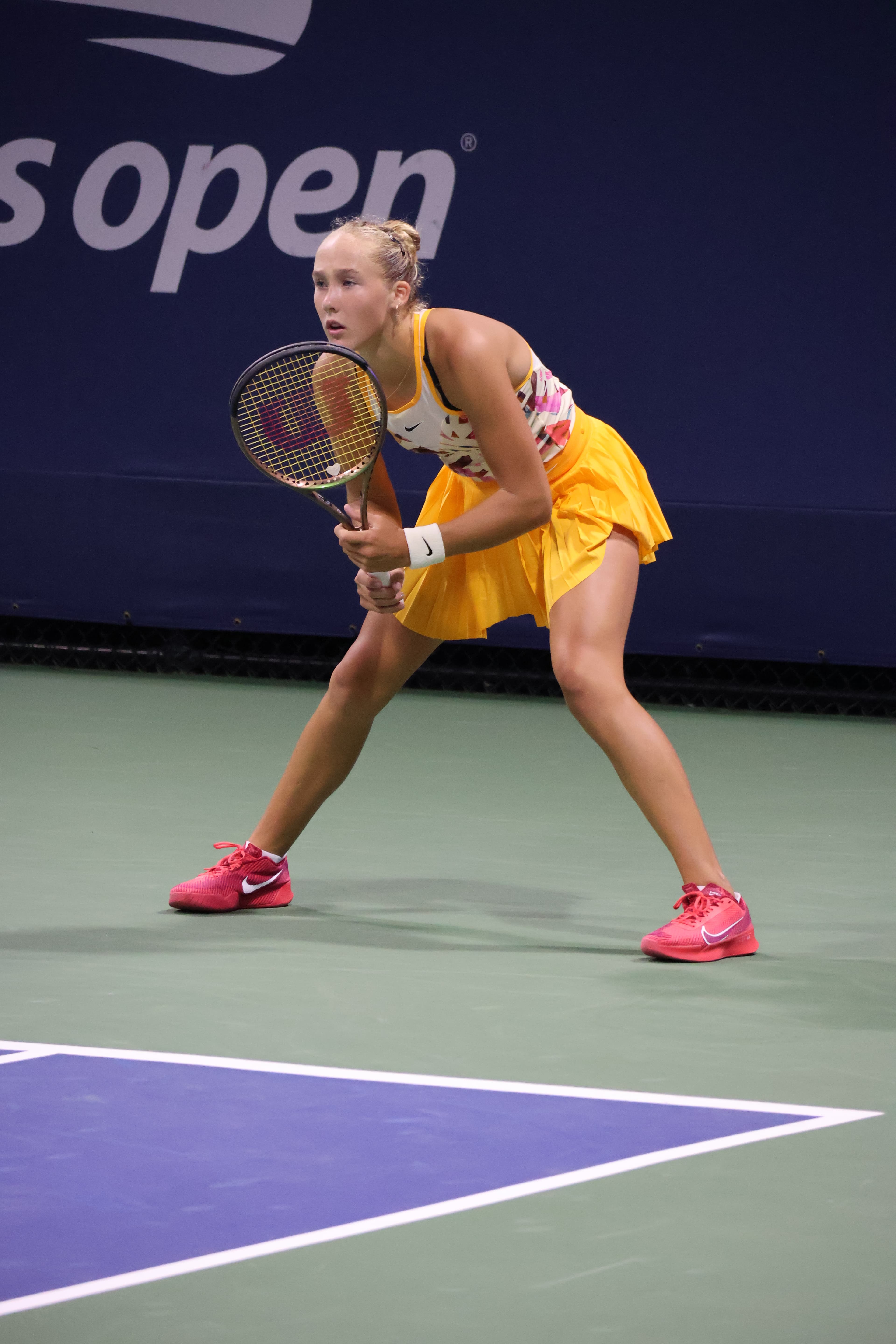 Mirra Andreeva at the 2023 US Open, photographed mid-match in a white kit holding her racquet